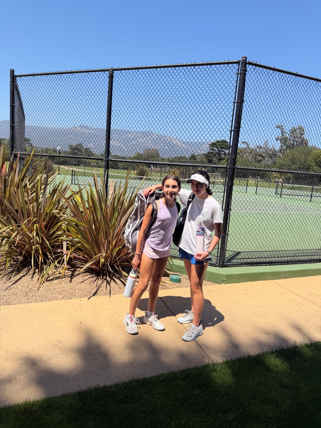 Gabriella with a friend at the tennis courts in front of the mountains